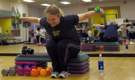 woman lifting small weights while seated